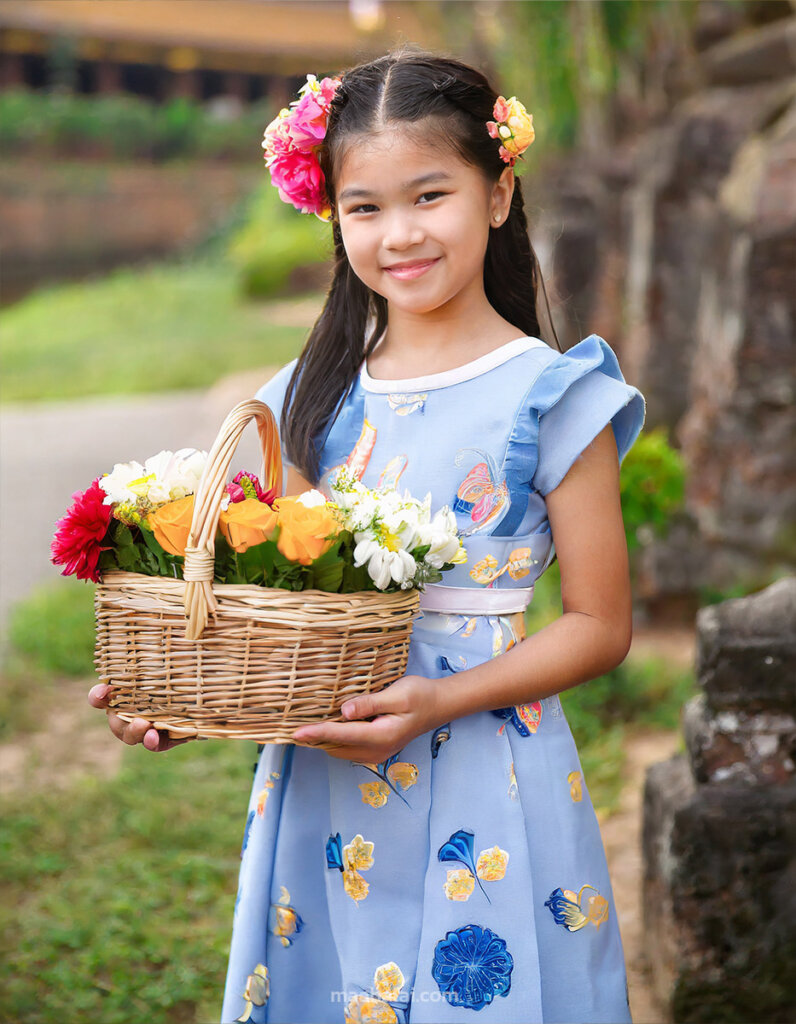 a young Thai girl wearing a flower girl dress and holding a basket of flowers art